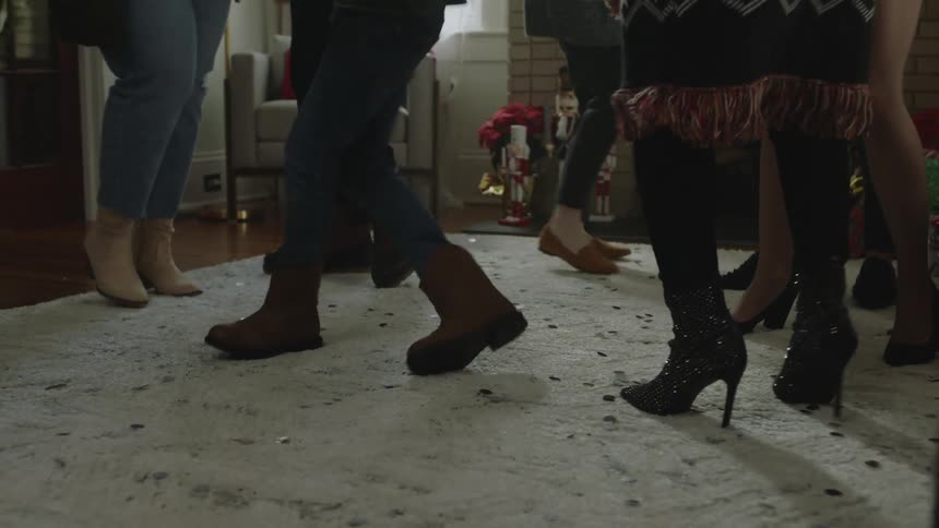 Closeup of peoples legs dancing in a room indoors and a boy slips and gets up shortly afterwards