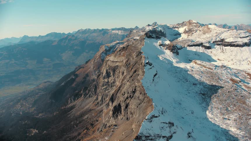 A mountain peak with slopes partially covered in snow