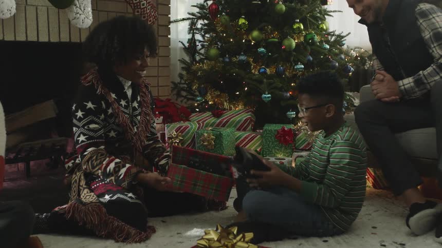 Son opens christmas gifts as parents watch