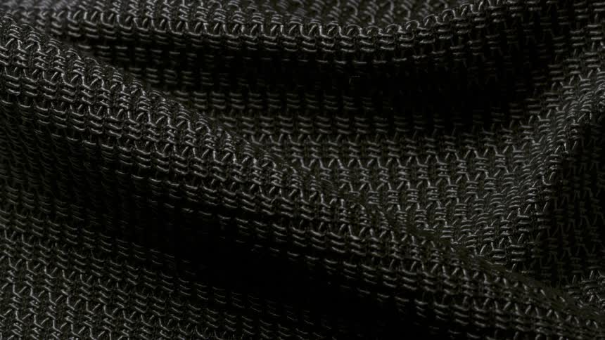A close up look of a black rough fabric with uneven texture under different lighting from bright to dark