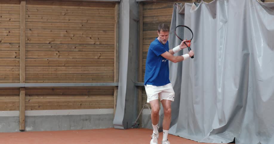Man playing tennis and using the racket to throw a ball