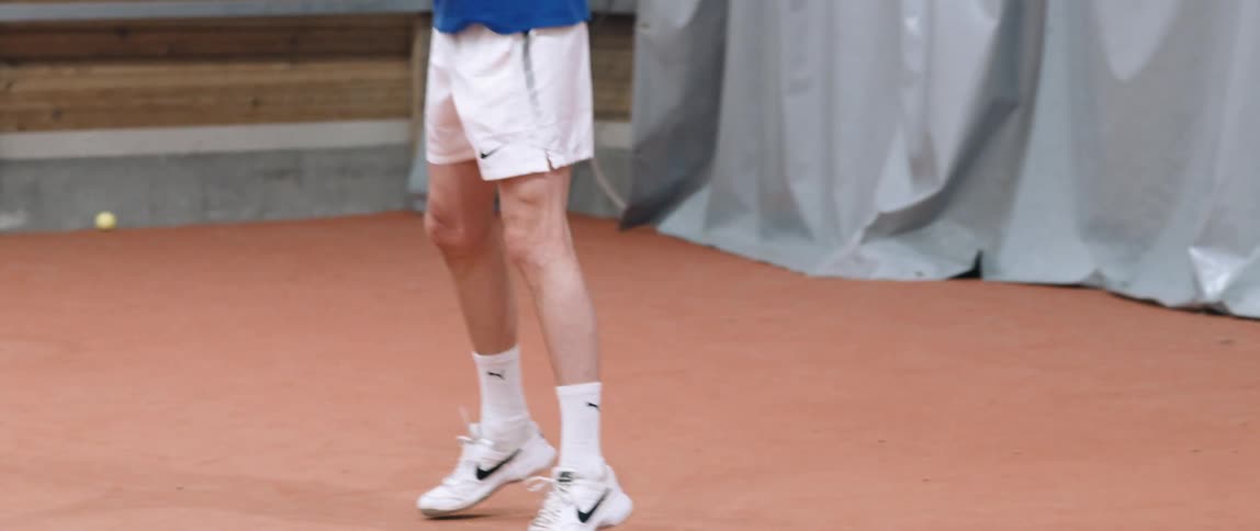 A man in long socks and sneakers running on a tennis court