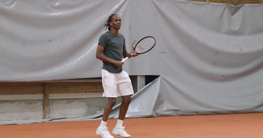 Black man playing tennis indoors