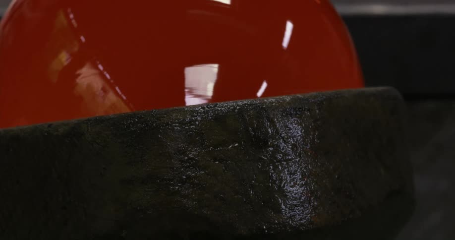 Sphere of redhot glass turning on a shaping tool