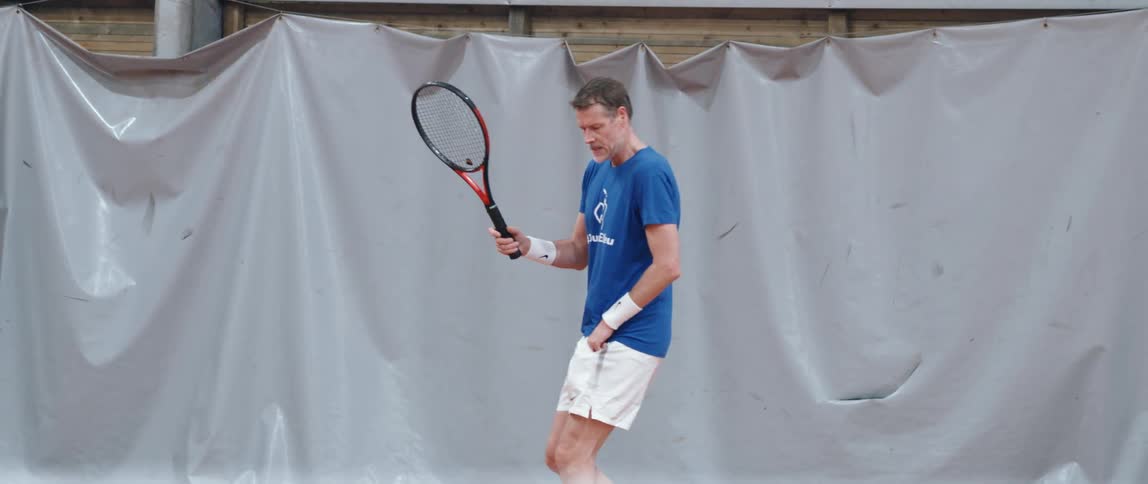 An adult man is hitting a tennis ball with a racket