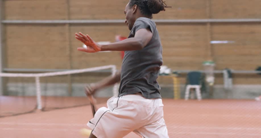 A man smashing a tennis ball on an indoor court