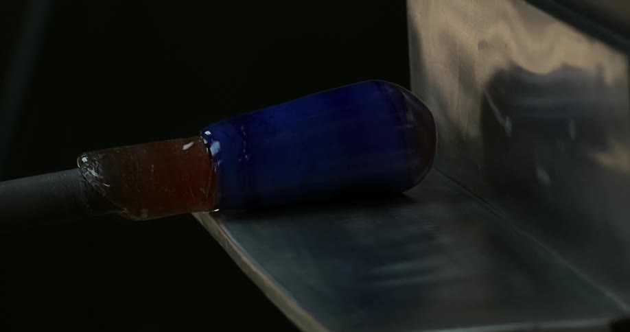 View of blue glass being shaped by a stake