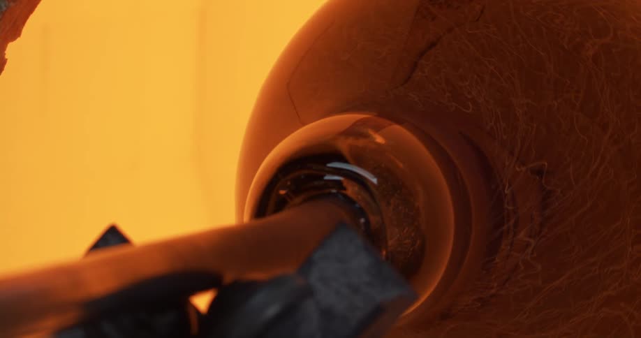 Molten glass rotates on end of staff during glass making