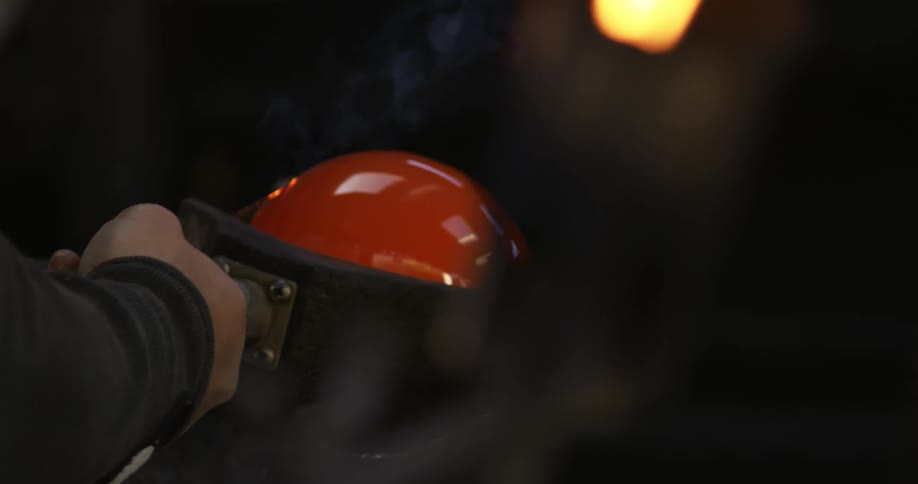 A persons hand placing a glass sphere in its solid state into a cooling process