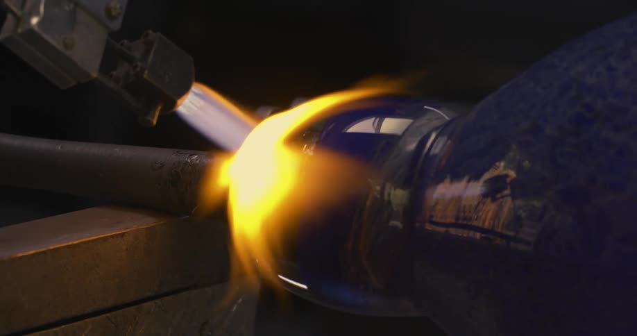 Blowtorch emitting flames on the finishing of a blue crystal vase