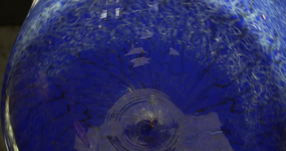 A blue glass vase with textures is rotating on an axis