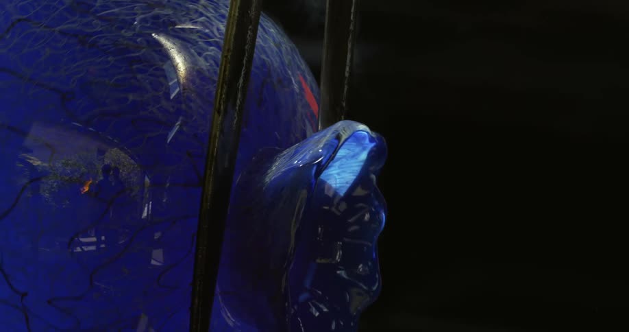 Metal thongs shape the neck of a piece of blue glassware