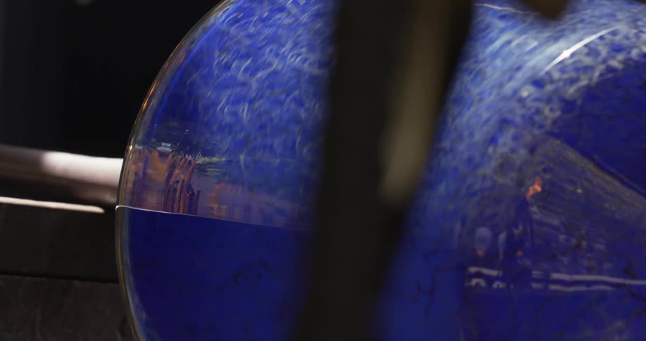 A spinning blue glass vase sitting on an iron tool