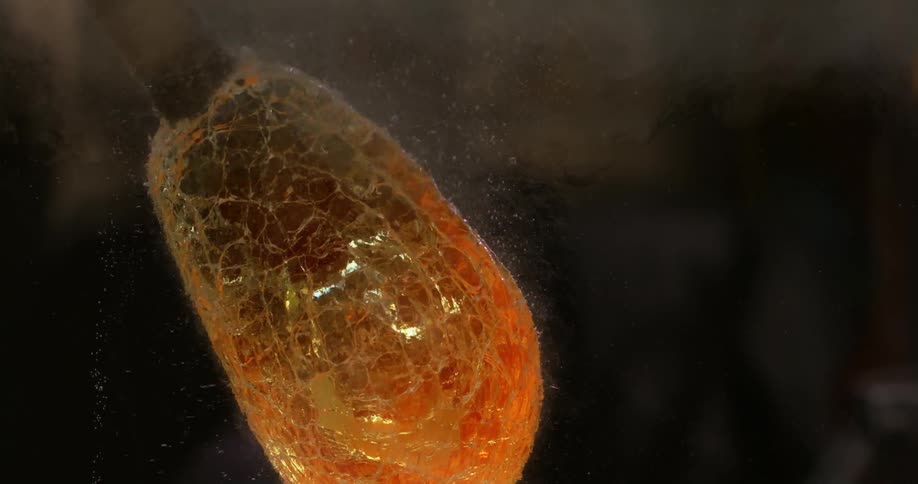 Molten glass mass stuck on post rotates in water creating bubbles