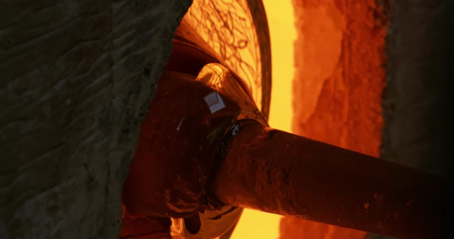 Translucent glass on end of staff rotates in furnace during glass making
