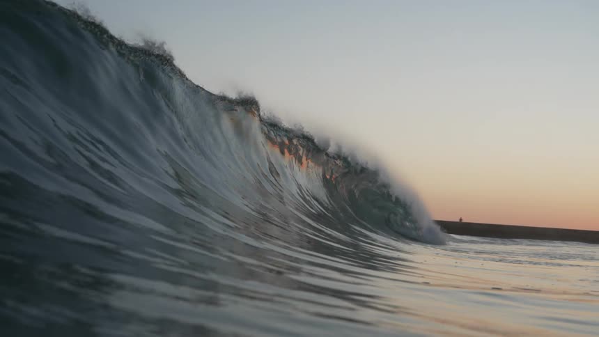 A wave splashes as it curls and rolls into shore and overhead