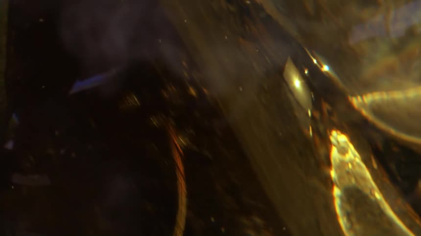 A bright bulb of glass rolling and reflecting yellow light