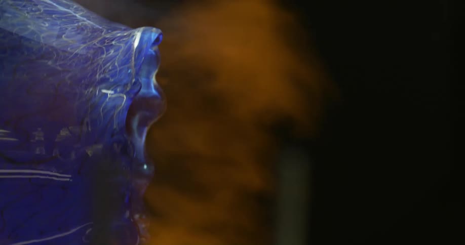 Blue glass vessel turns in flames during glass making