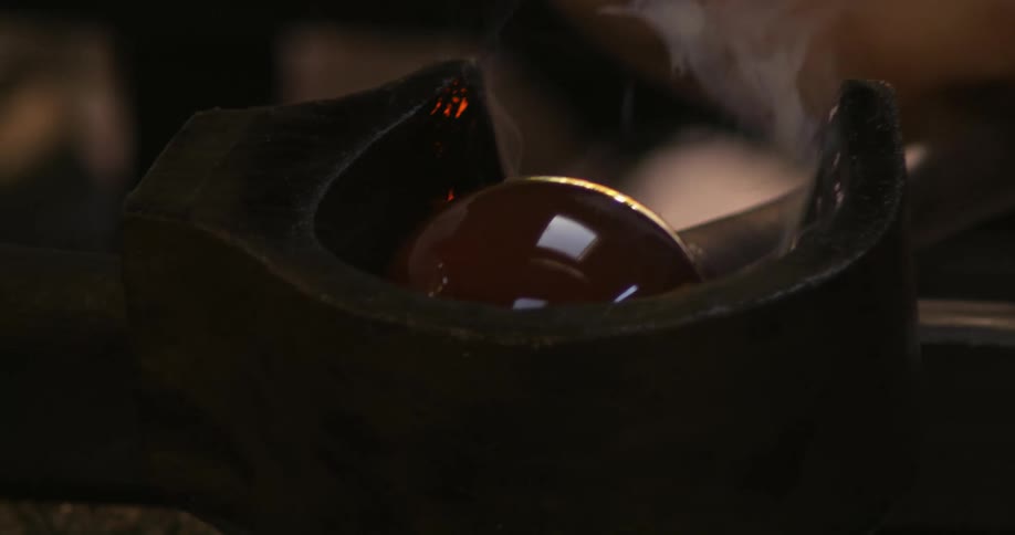 A glass sphere in production with smoke being emitted