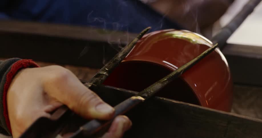 Hot piece of glassware being shaped with metal thongs