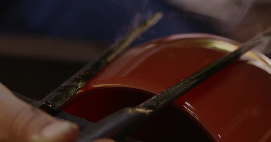 Metal thongs shape the exterior of a piece of spinning glassware