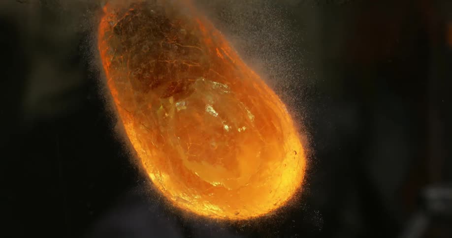 A metal tool with the hot tip glowing orange is submerged in water