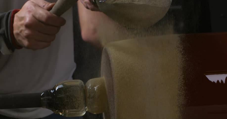 A man with a sieve pouring powder onto a glass jar
