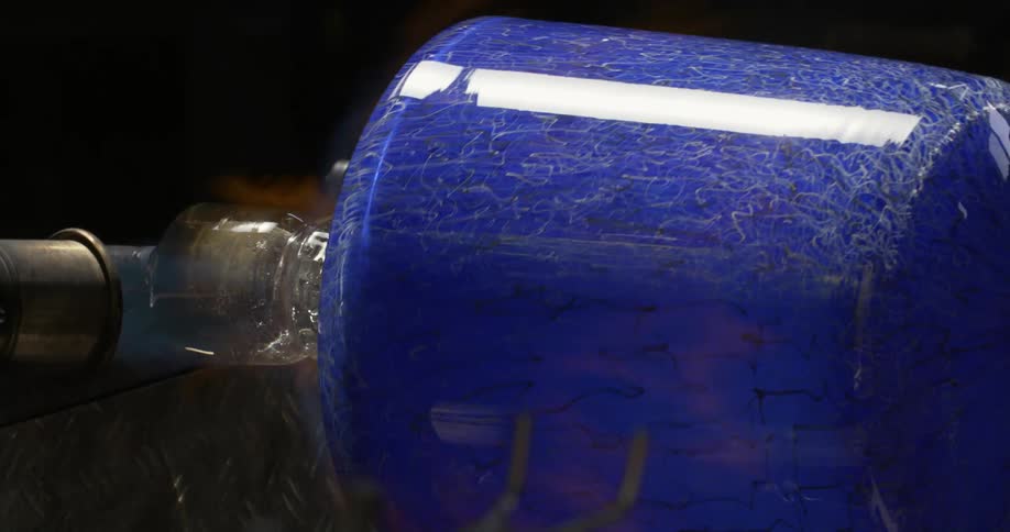 Close in a blue glass vase in production with flames passing