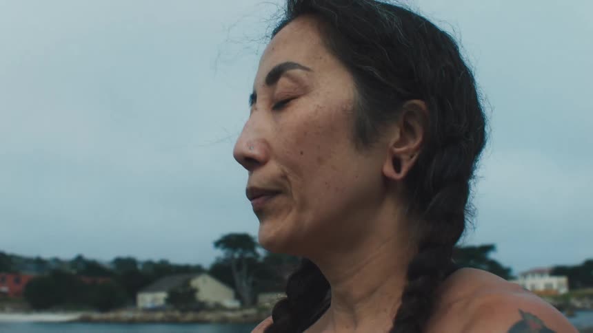 Woman taking deep breaths on a boat off the coast
