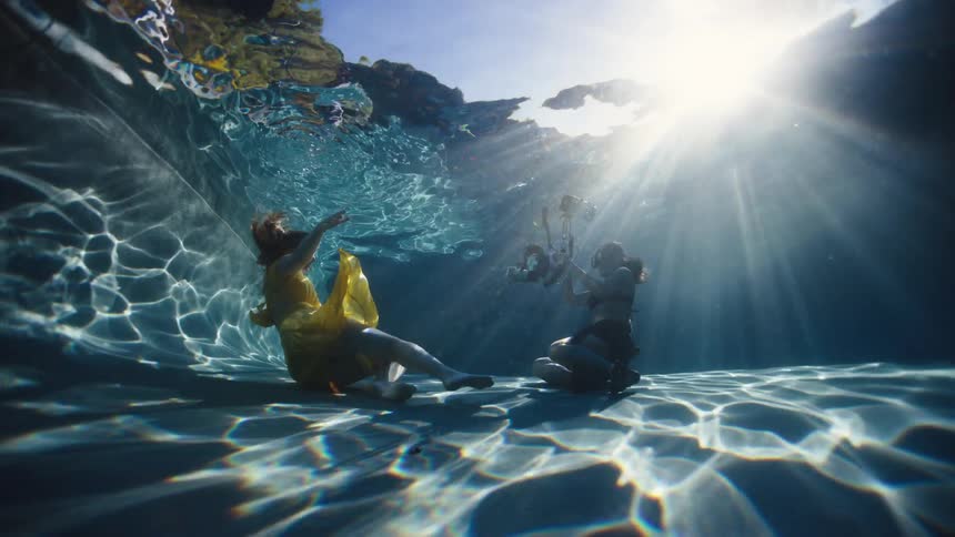 An underwater photo shoot takes place in a swimming pool