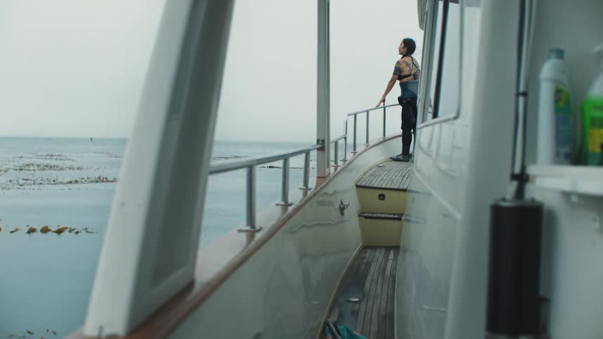 A woman stands on a boat looking out at the ocean