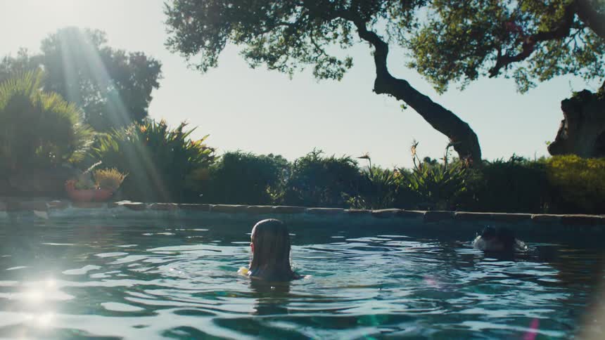 Two women in a backyard swimming pool at midday