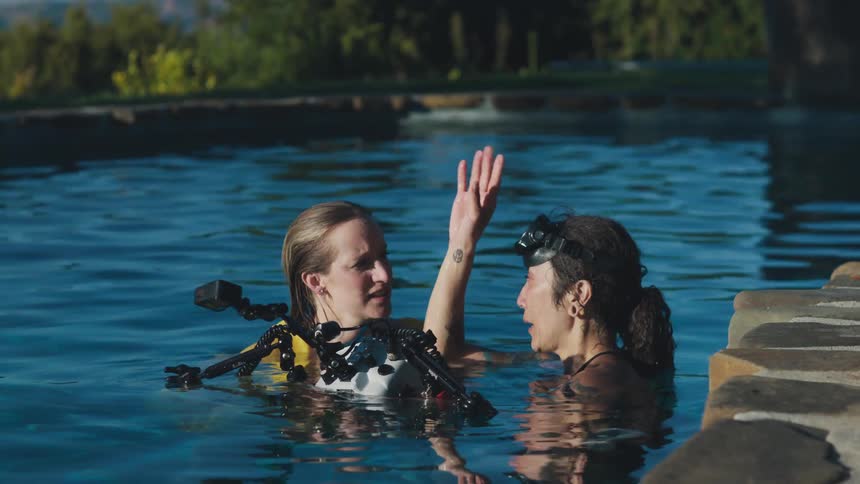 Two women reviewing photos taken in the pool underwater