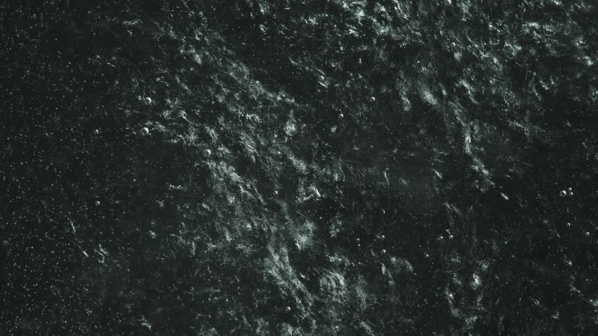 Small bubbles float over slow moving mass of black and white