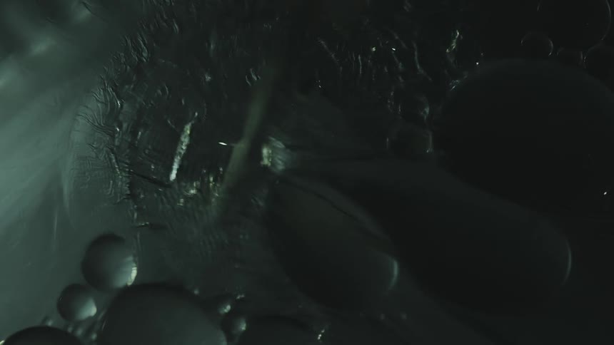 Bubbles flow across rippling gray surface near other floating bubbles