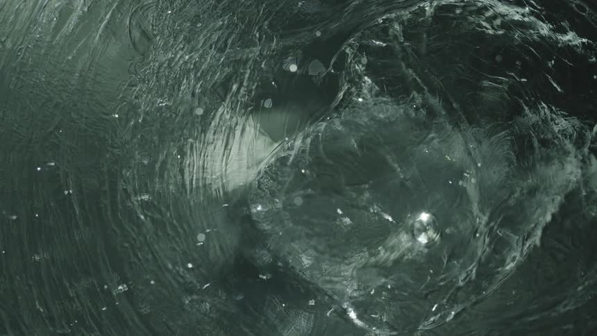 A droplet splashing into water and creating an impact in slow motion