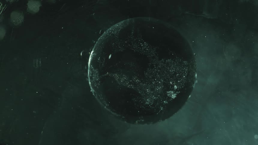 Large sphere decorated with a silver overlay rotates slowly surrounded by small bubbles