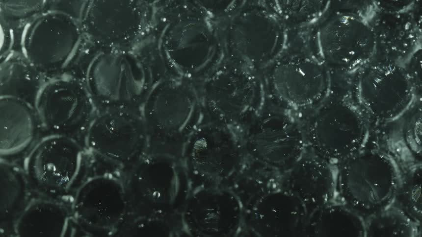 Small clear spheres reflect lights while floating on gray liquid