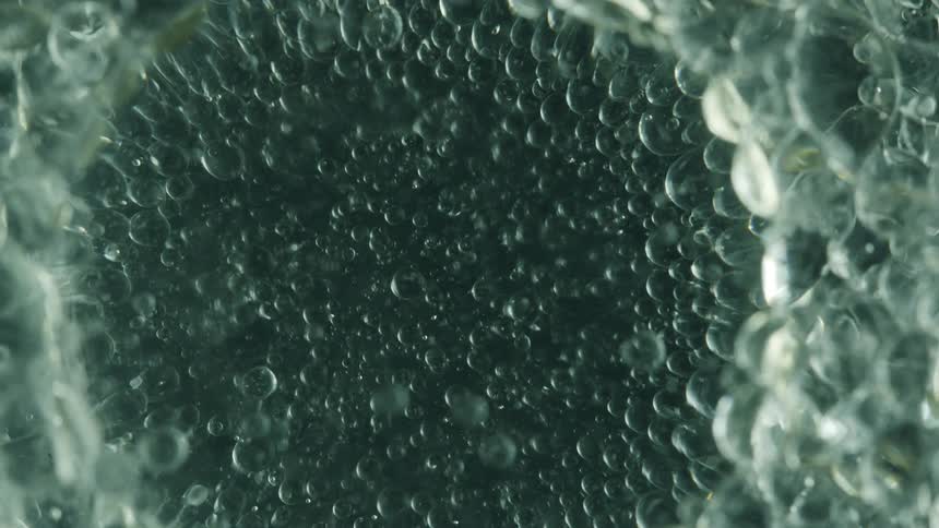 Extreme closeup of small abstract bubbles clustered in transparent liquid