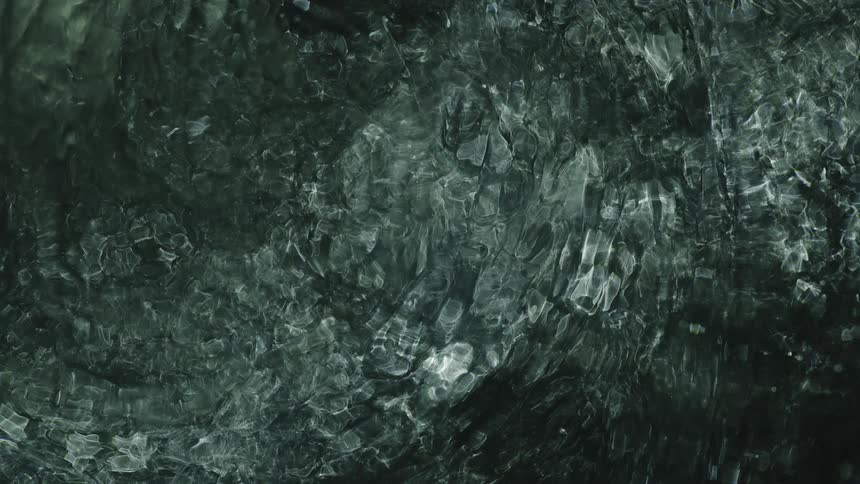Light shines from under surface of gray liquid