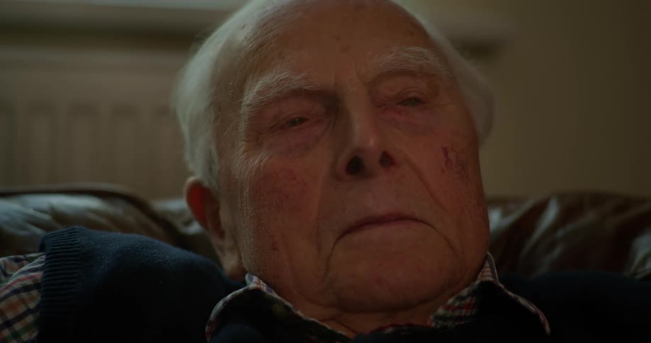 An elderly person sitting on the couch and dozing off