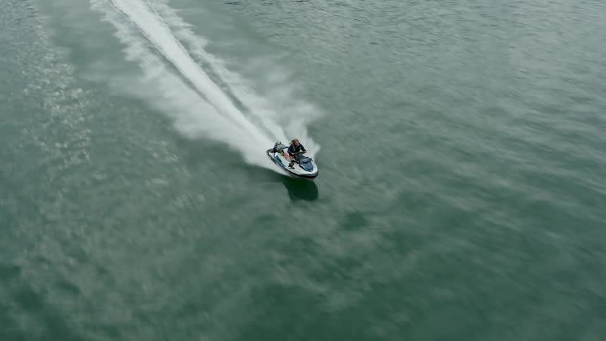 Woman rides jet ski across water leaving a wake