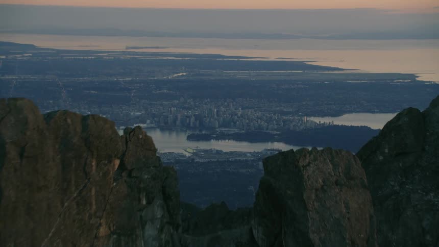 Aerial view of a waterfront city behind a mountain at evening