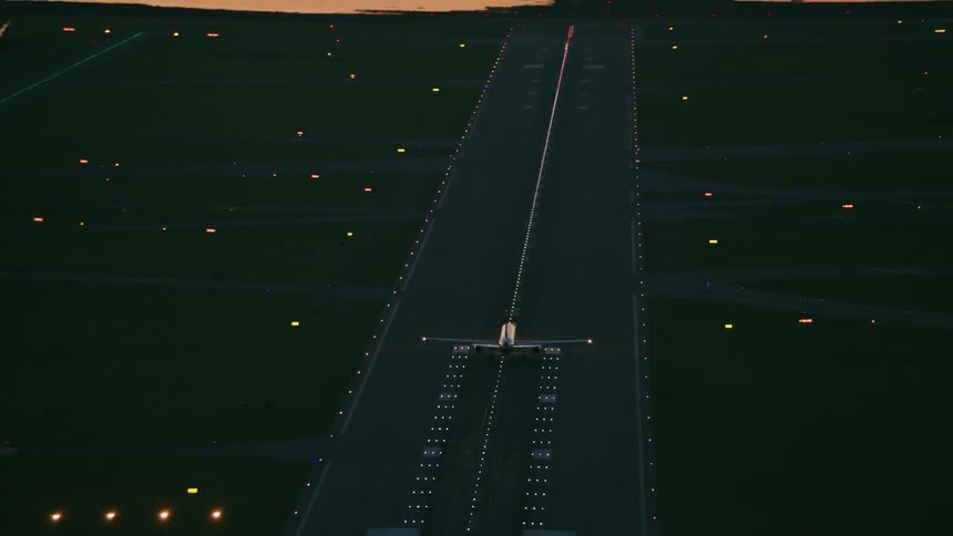 Airliner takes off from runway through red tinted sky after dusk