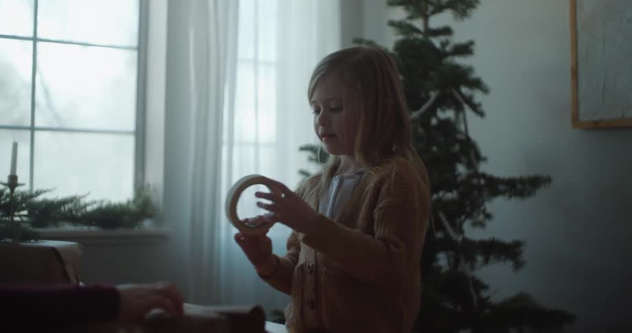 A parent and child wrap christmas presents together