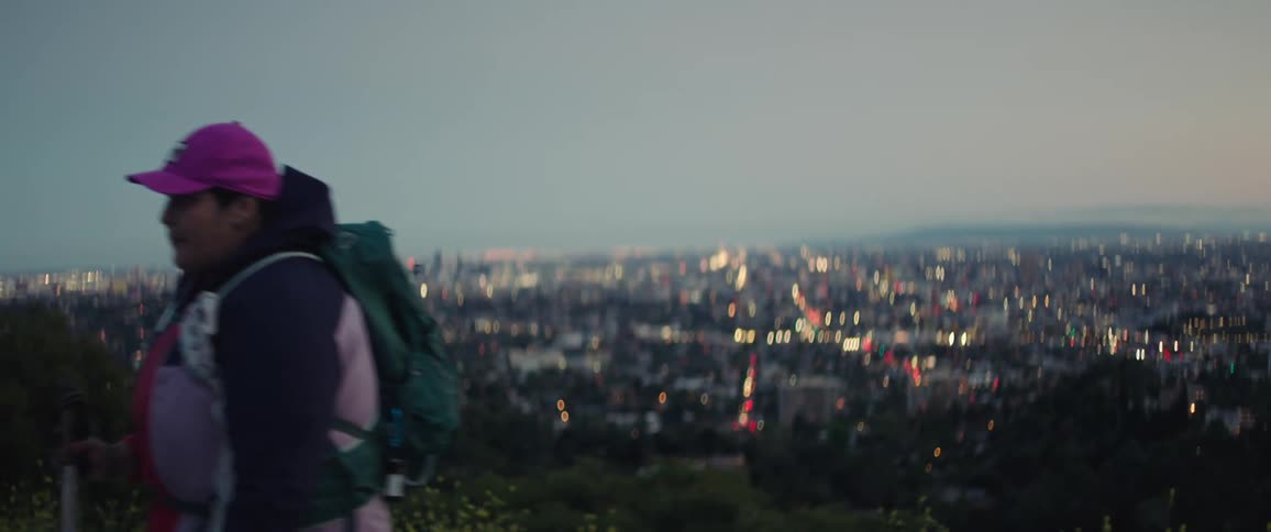 After dusk female walks with city skyline in the background