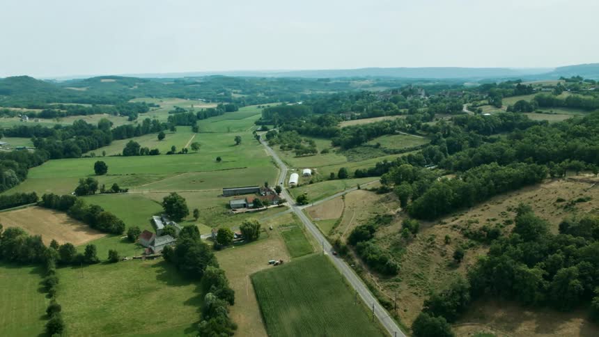 A rural region with green vegetation and a road with a car passing by