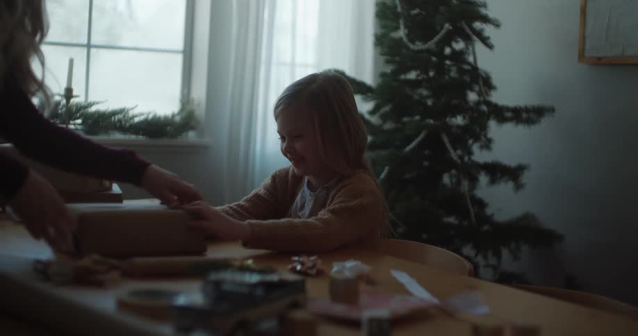 Mother and daughter talking indoor while wrapping a box