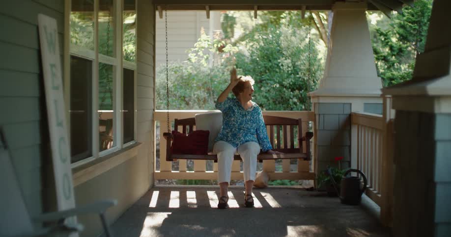 A woman waves from her porch