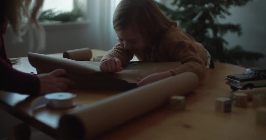 Mother and daughter wrap christmas gifts laughing and having fun